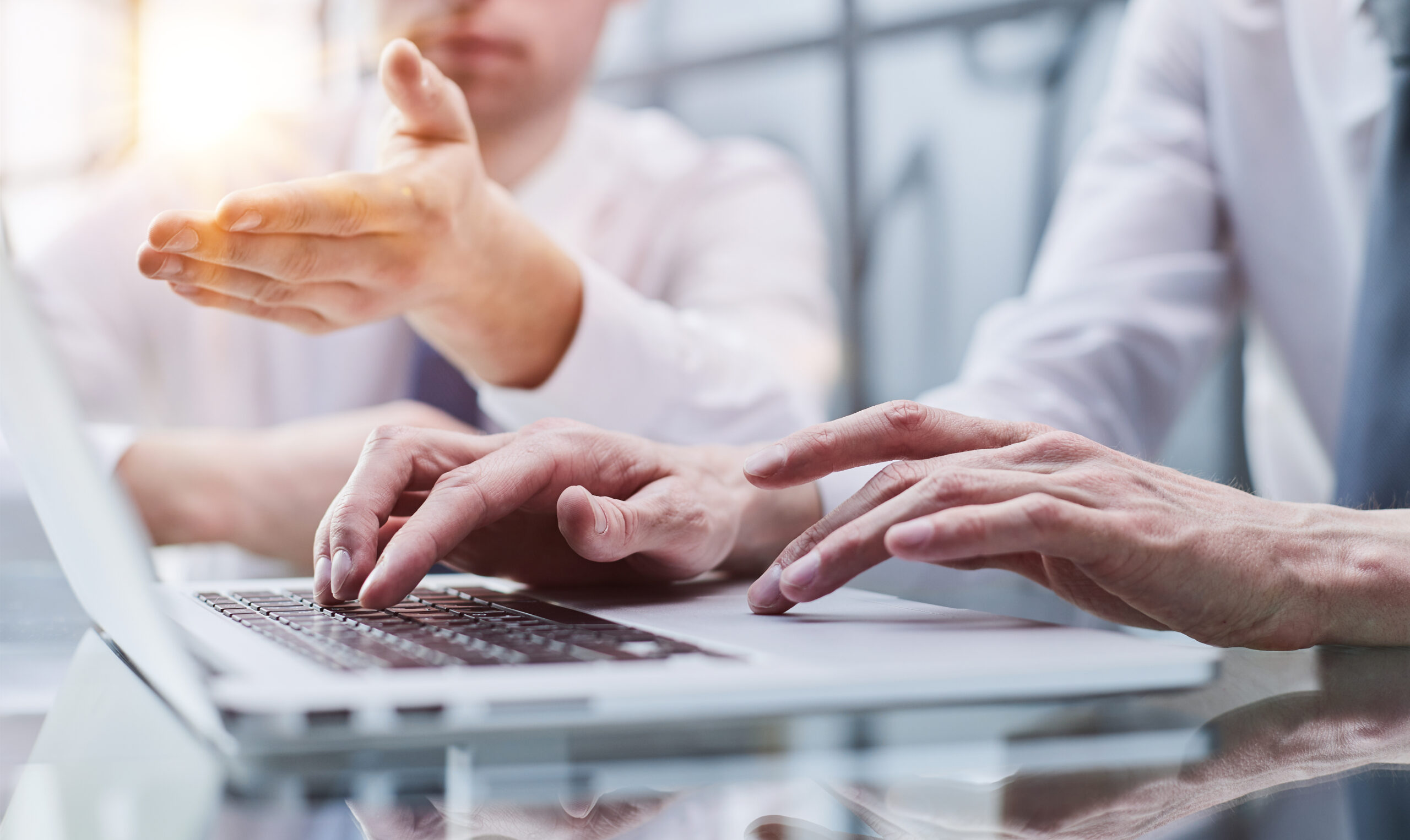 Closeup view of two young coworkers working on mobile laptop computer at office